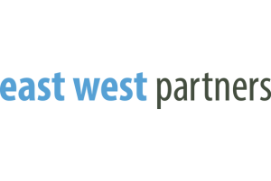 Logo of "east west partners" in lowercase blue letters, styled in a simple, modern font, representing local businesses.